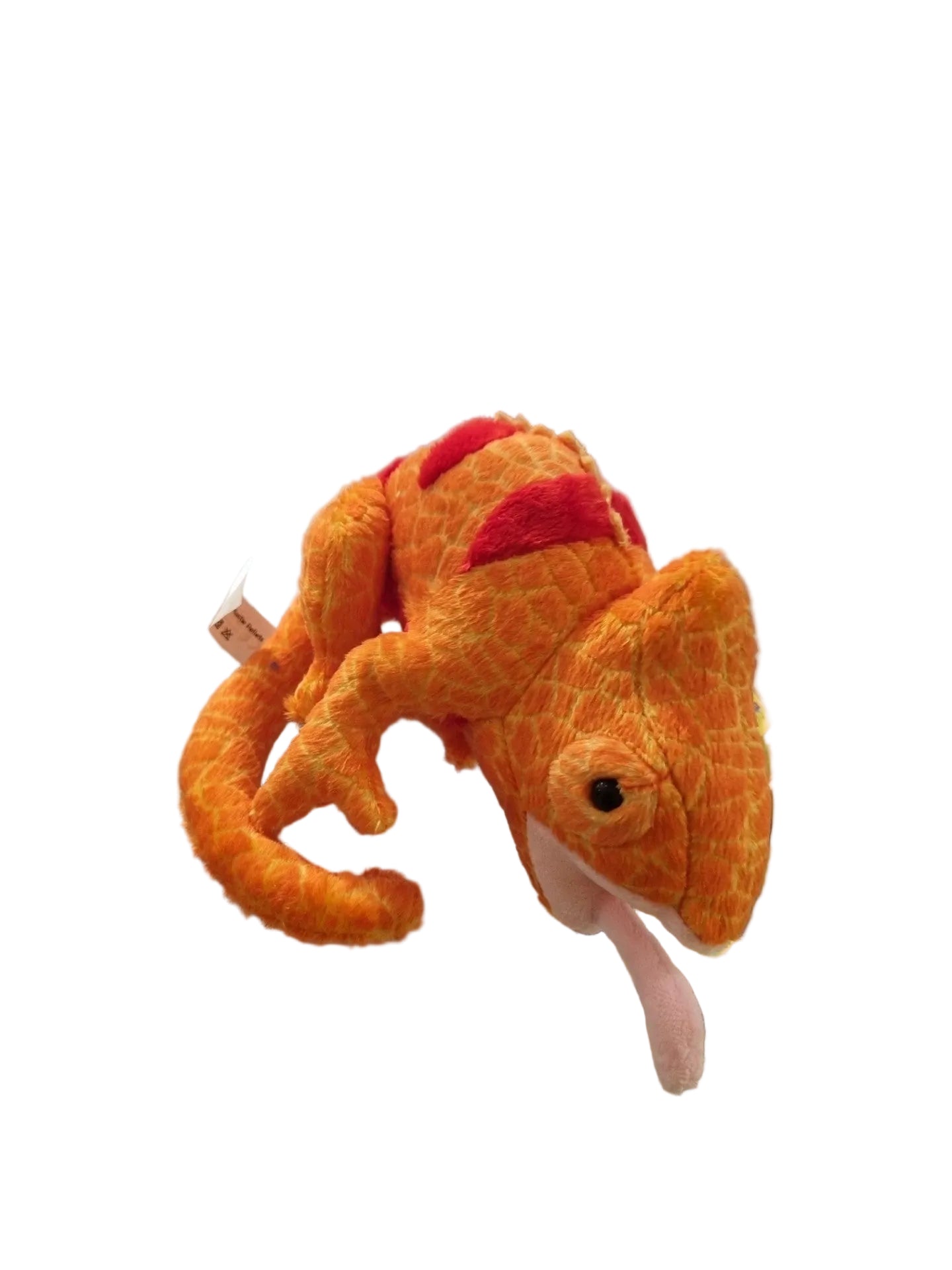An orange plush chameleon toy with red spots and a pink tongue, resting on a glass display counter in a retail store.