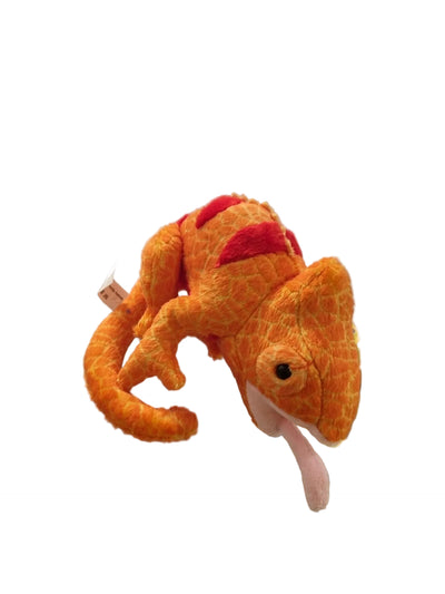 An orange plush chameleon toy with red spots and a pink tongue, resting on a glass display counter in a retail store.