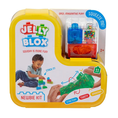 Jelly Blox Newbie Kit toy packaging, featuring a bright yellow plastic case with a clear window showing blue and multicolor jelly blocks, plus instructional graphics and a child playing with the toys.