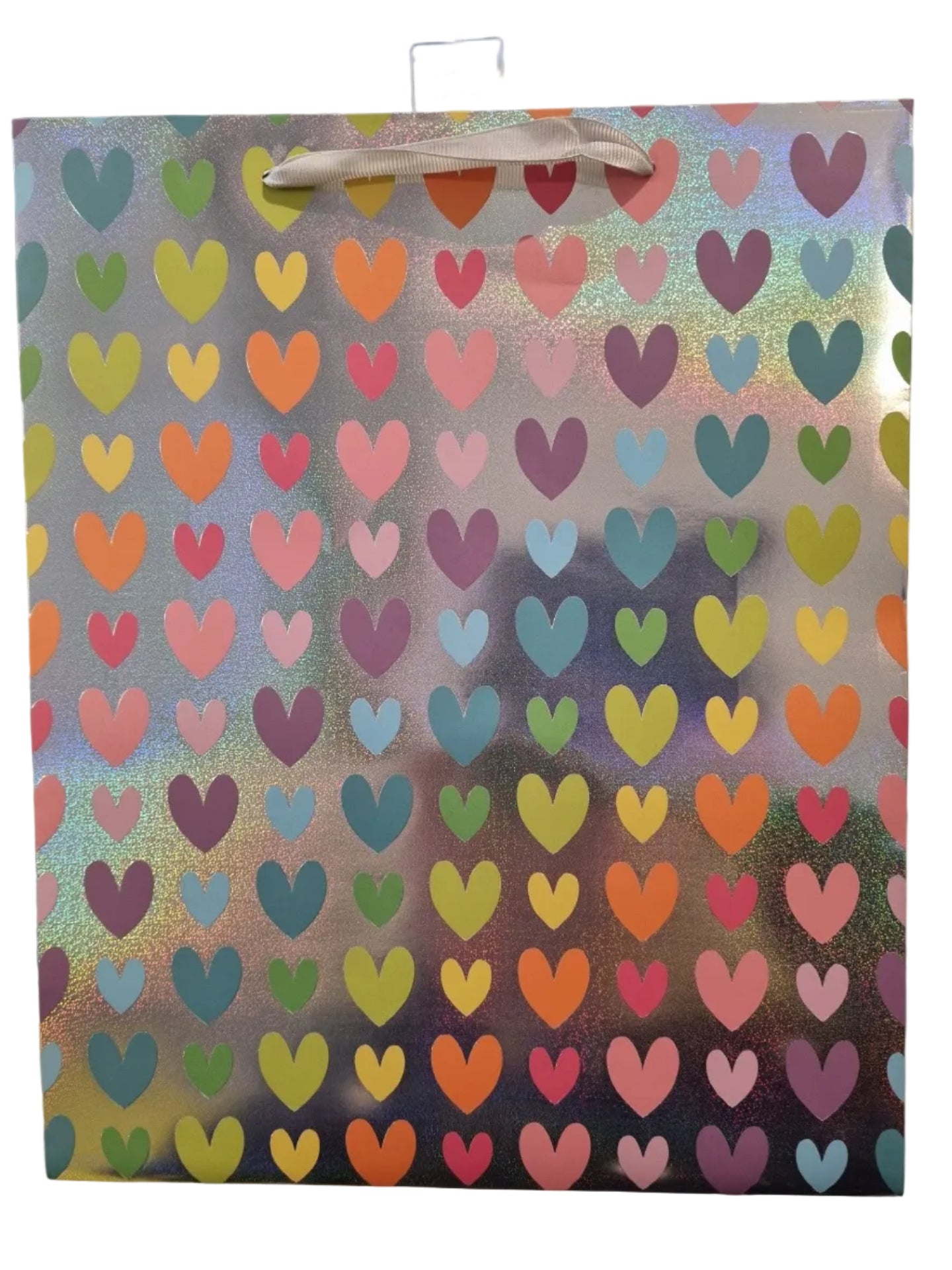A square gift bag with a holographic silver background covered in a repeating pattern of colorful hearts in pink, orange, yellow, green, blue, and purple. A white paper handle is attached to the left side.