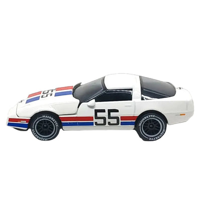A white die-cast model Corvette race car with red and blue stripes and the number 55 on the side, shown against a solid black background.