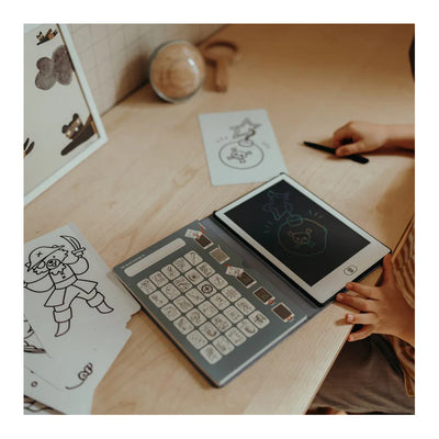 Children's drawing tablet with keyboard on a wooden table, surrounded by cartoon drawings.