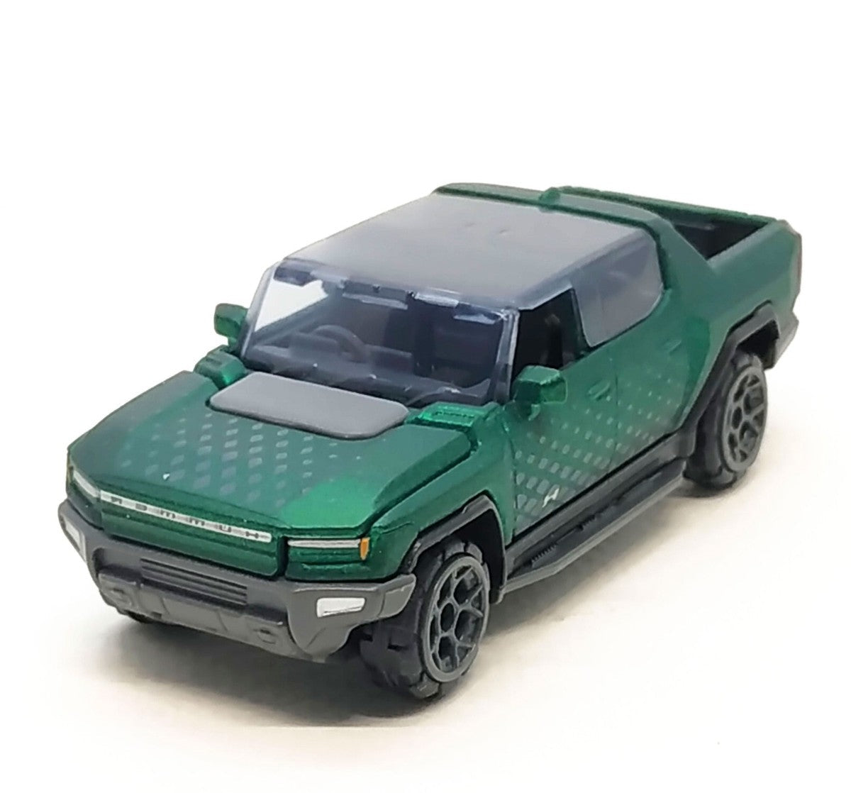 A green die-cast toy pickup truck with a dark gray roof and wheels, shown on a white background. A small inset image in the top right corner displays a black rectangular item labeled 'Free!!!'.