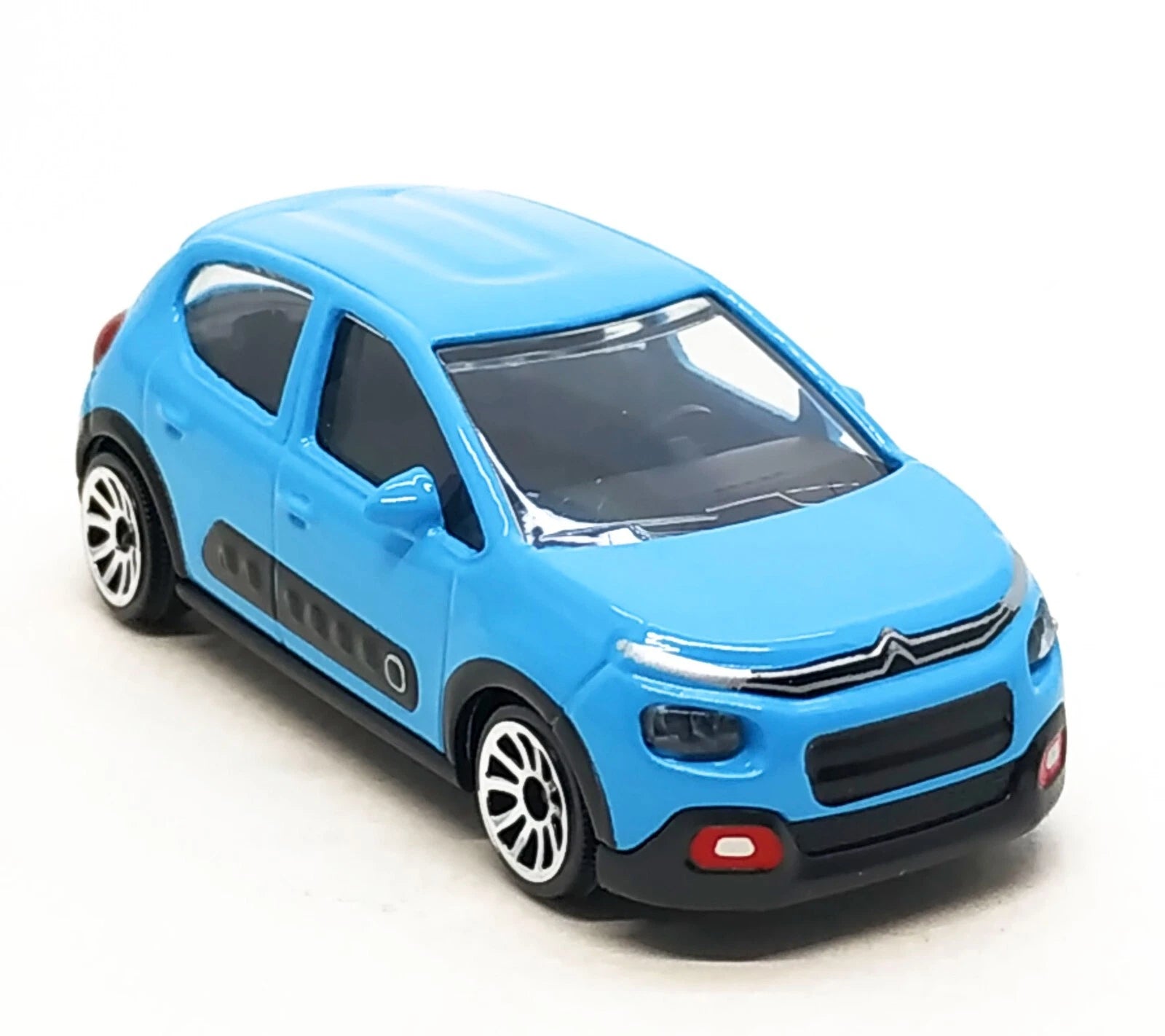 A blue toy model car resembling a Citroèn C2, shown from a three-quarters front angle on a clean white background.